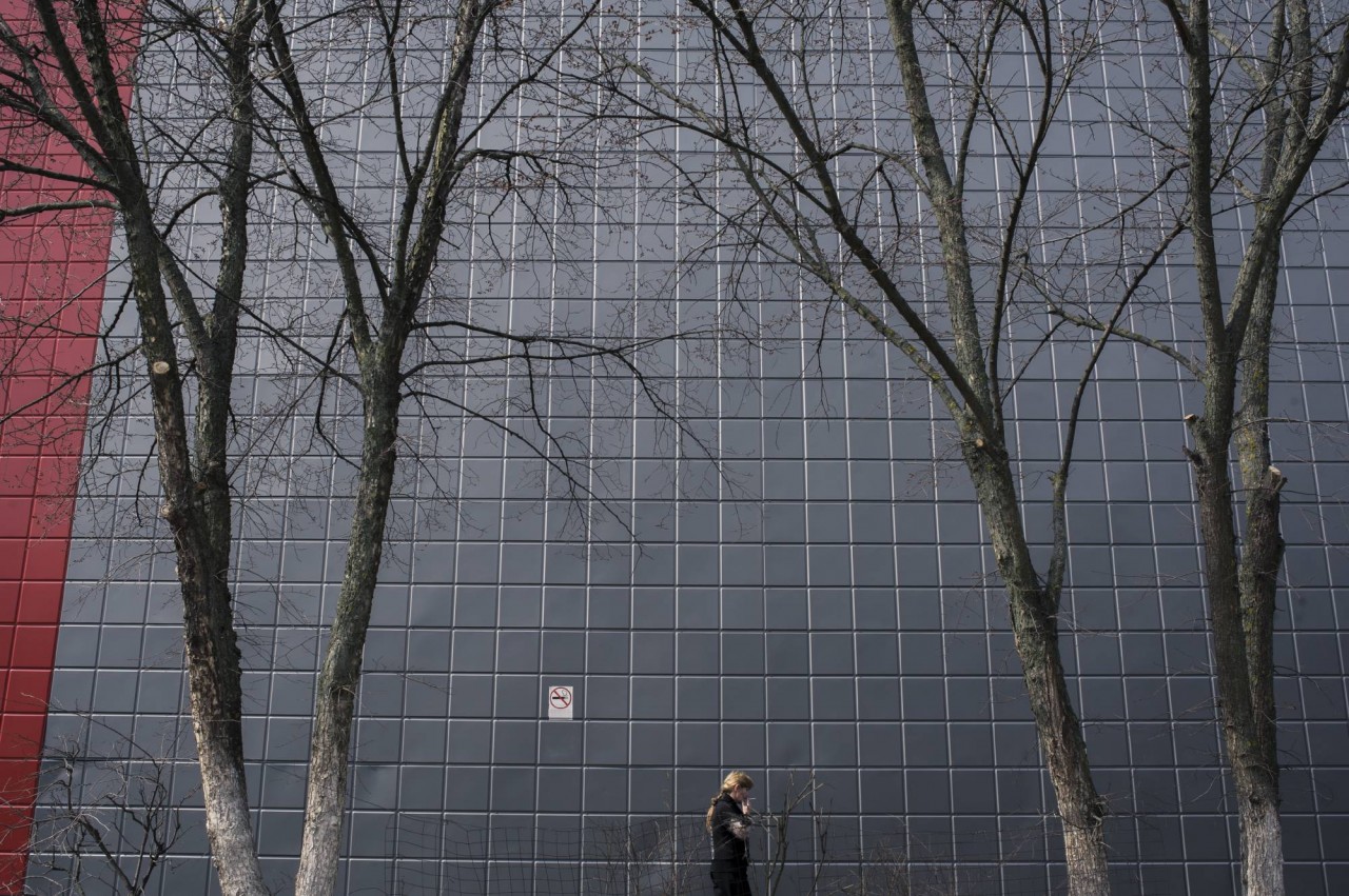 Женщина идет мимо здания торгового центра в промышленном районе 
