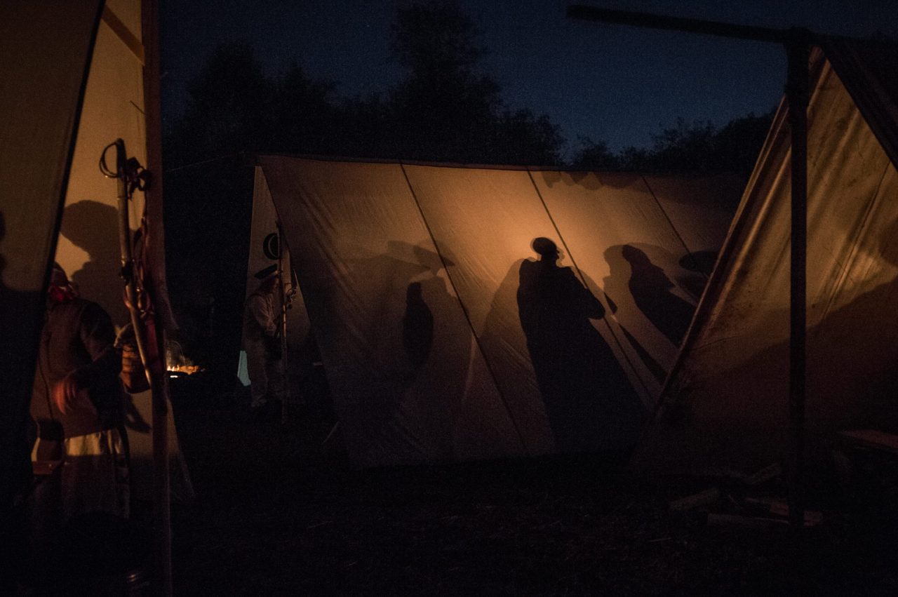 Тени реконструкторов на стене палатки в лагере вечером во время ужина