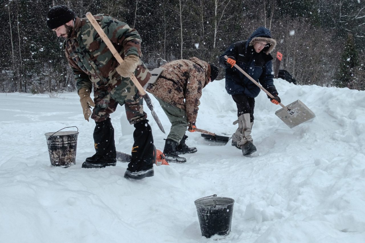 Участники подготовительных работ вырезают из прессованного снега кирпичи для строительства Снежной Крепости 