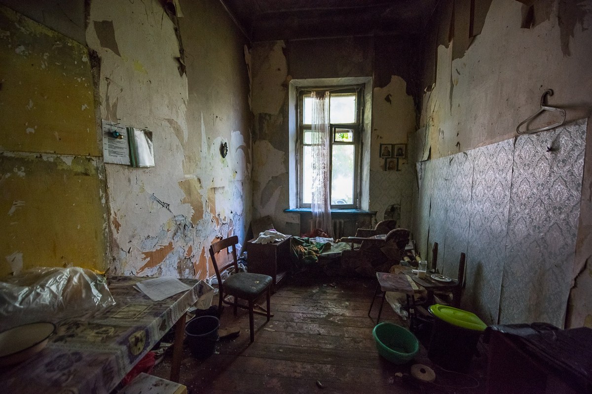  На фото очень бедное жилище: ободранные стены, полуразвалившаяся мебель, грязь.
