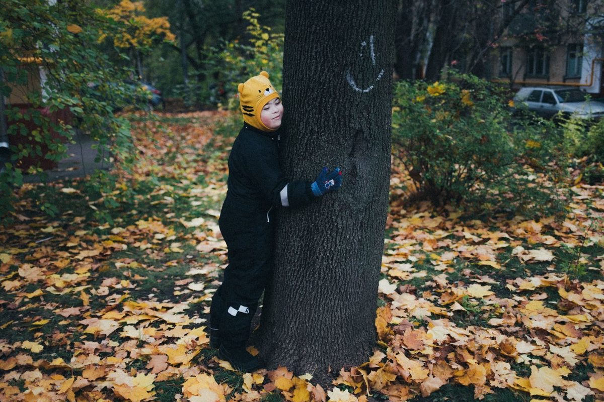  На фотографии ребенок в яркой одежде играет среди деревьев гордского сквера